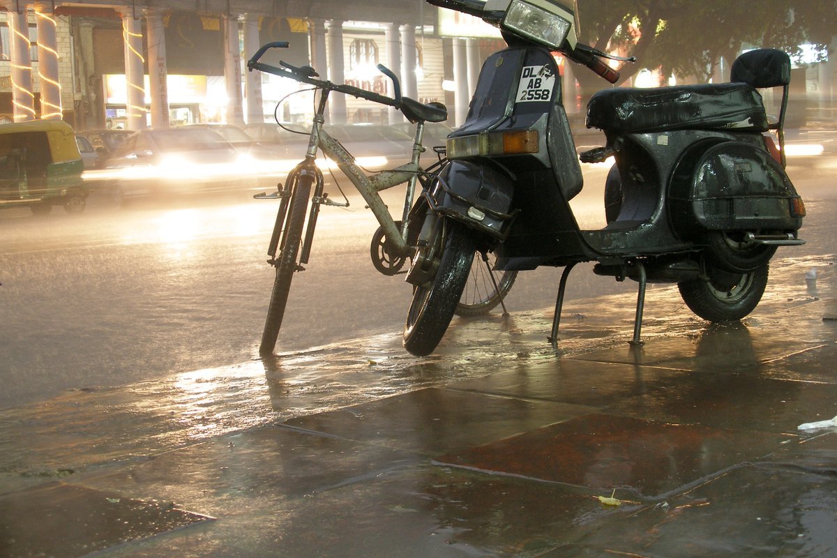 दिल्ली रेन: कनॉट प्लेस इलाके में भीगती सड़क और खड़ी स्कूटर