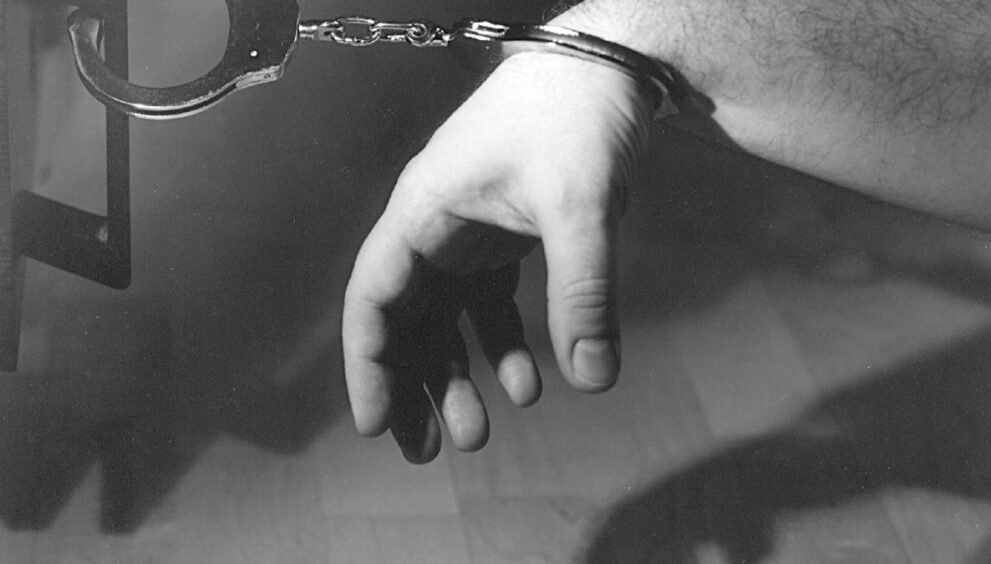 पुलिस की हथकड़ी पहने हाथ की सांकेतिक तस्वीर