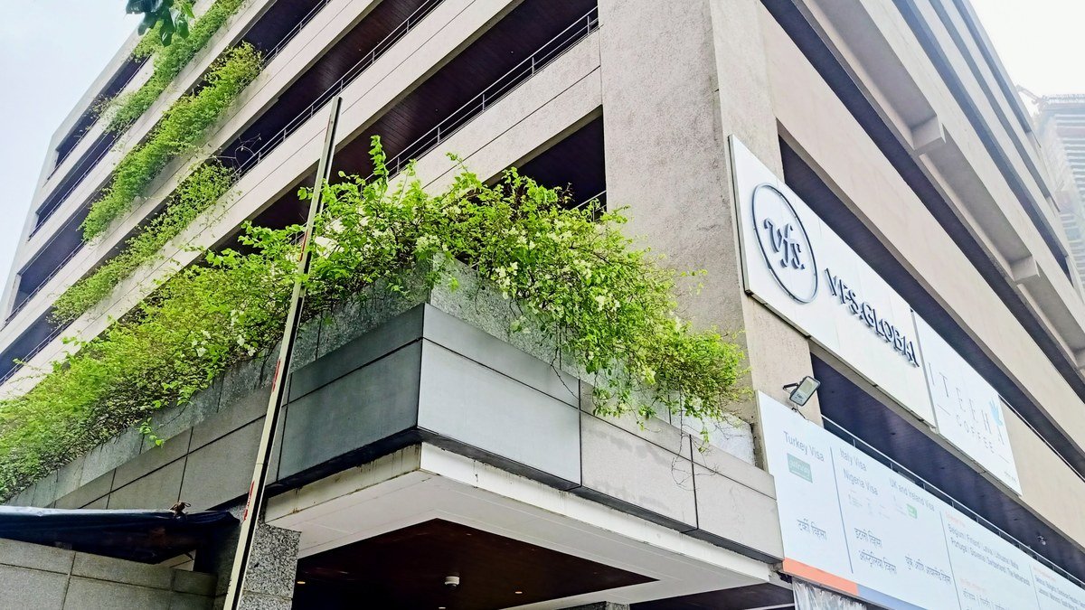 मुंबई में VFS Global की इमारत, जिस पर कंपनी का बोर्ड और हरी बेलें लगी हैं