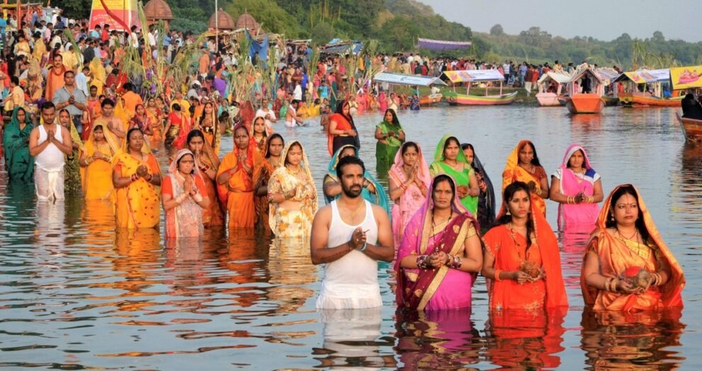 छठ पूजा पर नदी में खड़े होकर हाथ जोड़कर सूर्य की उपासना करते व्रती