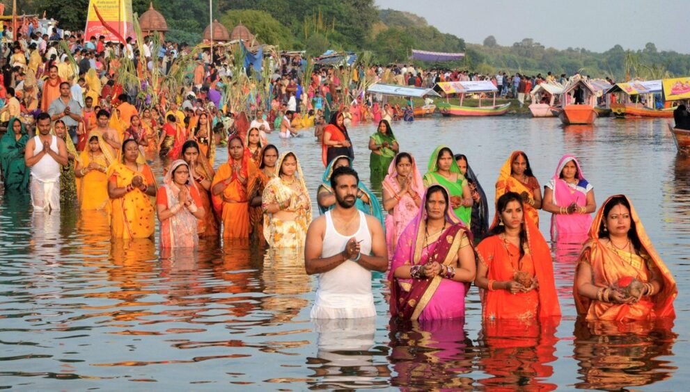 छठ पूजा पर नदी में खड़े होकर हाथ जोड़कर सूर्य की उपासना करते व्रती
