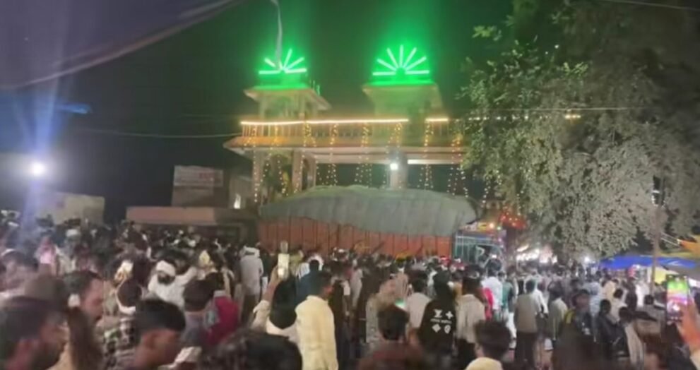 ग्वालियर में शीतला माता मंदिर के गेट के पास हादसे के बाद खड़ा धान से लदा ट्रक और जुटी भीड़