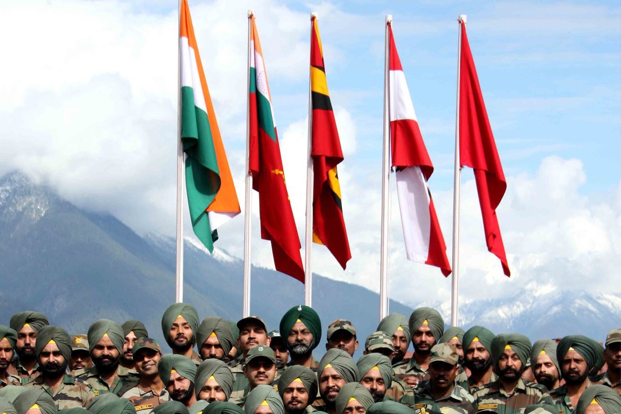 अरुणाचल प्रदेश के किबिथू में बर्फीले पहाड़ों के सामने तिरंगे और रेजिमेंटल झंडों के नीचे खड़े भारतीय सेना के जवान