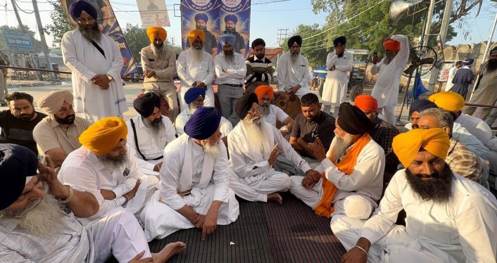 मानसा में परविंदर सिंह झोटा के लिए इंसाफ की मांग पर धरने में बैठे सिख नेता और समर्थक, पीछे झोटा के पोस्टर